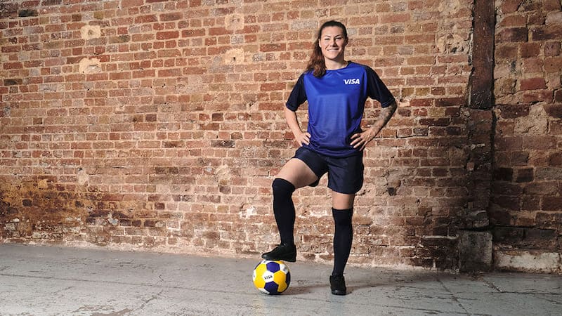 Team Visa Athletin Ramona Bachmann mit Visa Fussball vor Backsteinwand