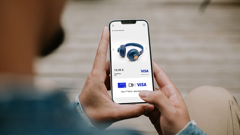 Mann shoppt Kopfhörer über Click to Pay mit Visa über sein Smartphone-Display